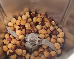 Step <h4><b>Ir poniendo los granos de avellanas en el vaso del Thermomix, colocar el cubilete y seleccionar 10 segundos, velocidad 10 para pulverizar todos los granos de avellanas.<br>Terminado los 10 segundos, bajar con la espátula todo lo que queda en las paredes del vaso (Repetir el proceso 3 veces).</b></h4> illustration